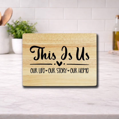 Engraved cutting board with the phrase 'This Is Us: Our Life, Our Story, Our Home' elegantly displayed.